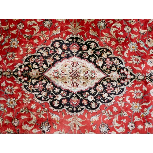 397 - A Persian pure silk rug, decorated with birds, flora and foliate, on a red ground with a black borde... 