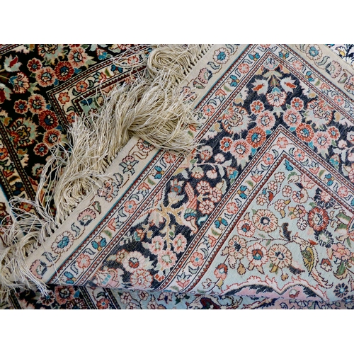 406 - A pair of silk rugs, each decorated with flowers, trees and birds, on a multi-coloured ground  ... 