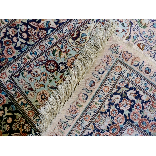 406 - A pair of silk rugs, each decorated with flowers, trees and birds, on a multi-coloured ground  ... 