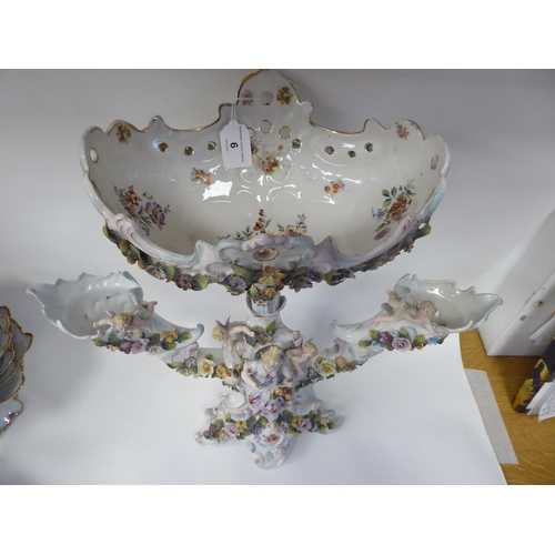 6 - A Continental porcelain, floral encrusted table centrepiece, comprising a central basket, flanked by... 