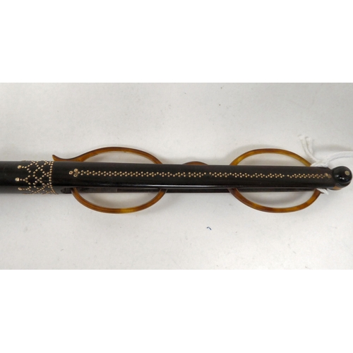 62 - A 19thC piquetworked tortoiseshell lorgnette, the lenses folding into a wand; and a 19thC eyeglass, ... 