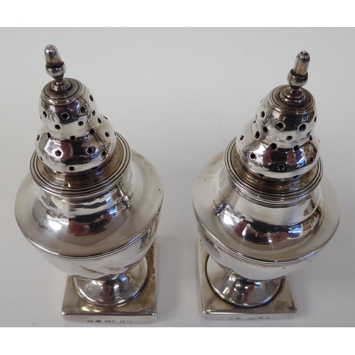 94 - A pair of Georgian silver, loaded pedestal, vase design pepper pots with detachable lids and finials... 