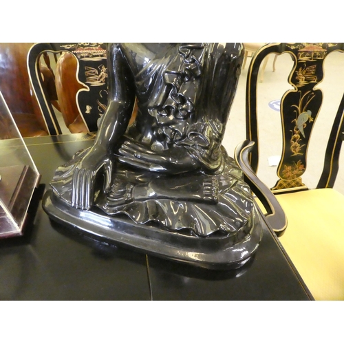 303 - A black painted ceramic model, a seated Buddha  24