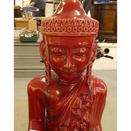 313 - A dark red painted ceramic model, a seated Buddha  24