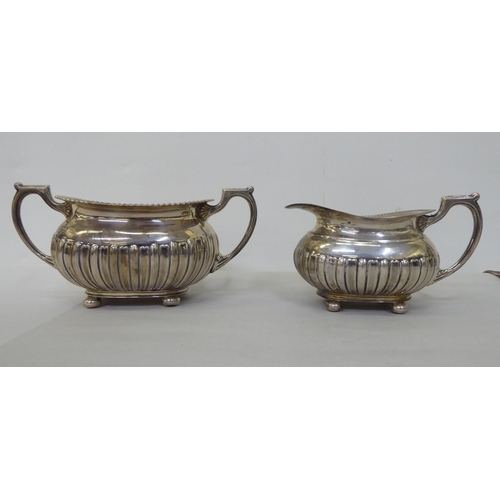 82 - An Edwardian Walker & Hall silver three piece tea set of oval, demi-reeded form  Sheffield 1906 ... 