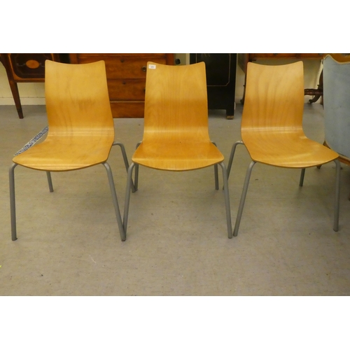 251 - Three modern Ness steel framed and laminated oak stacking chairs  bearing a label