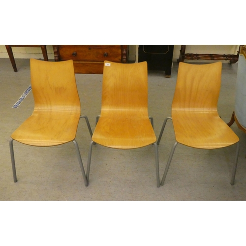 251 - Three modern Ness steel framed and laminated oak stacking chairs  bearing a label