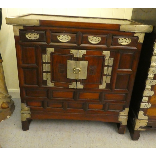 296 - A mid 20thC Chinese elm metal bound cabinet with four short drawers and two doors, raised on bracket... 