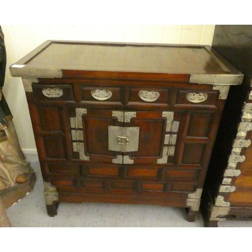 296 - A mid 20thC Chinese elm metal bound cabinet with four short drawers and two doors, raised on bracket... 