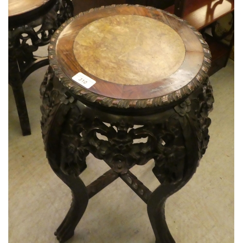 310 - A late 19thC profusely carved teak jardinière stand with an inset marble top, raised on cabri... 