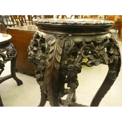 310 - A late 19thC profusely carved teak jardinière stand with an inset marble top, raised on cabri... 