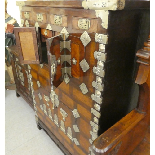 326 - A mid 20thC Chinese elm metal bound cabinet with four short drawers and four doors, raised on bracke... 