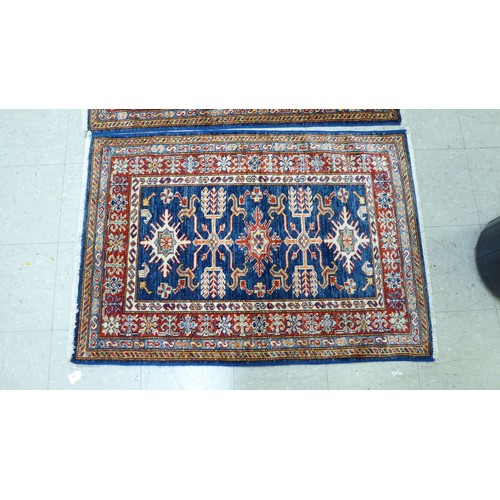 24 - A pair of Persian rugs, decorated with repeating stylised designs, on a multi-coloured ground  32