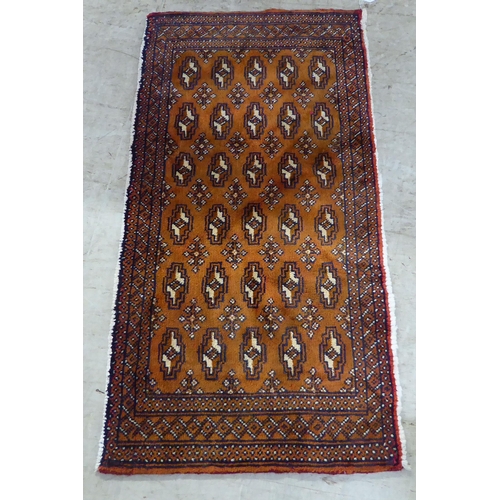 118 - A Persian Bokhara design rug, decorated with geometric patterns, on a red ground  52