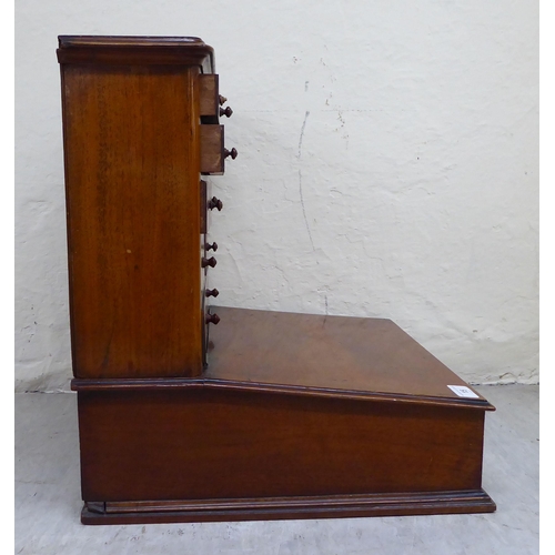 15 - An early/mid 20thC two-part mahogany desk top organiser, the upper section with eleven drawers, over... 