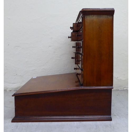 15 - An early/mid 20thC two-part mahogany desk top organiser, the upper section with eleven drawers, over... 