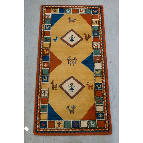 381 - A modern D&C Qashqai machine made rug, decorated with figures and animals, on a multi-coloured g... 