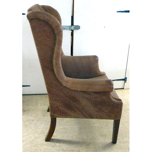 71 - An early 20thC Georgian reproduction of a stud upholstered, enclosed arm, high back chair, raised on... 