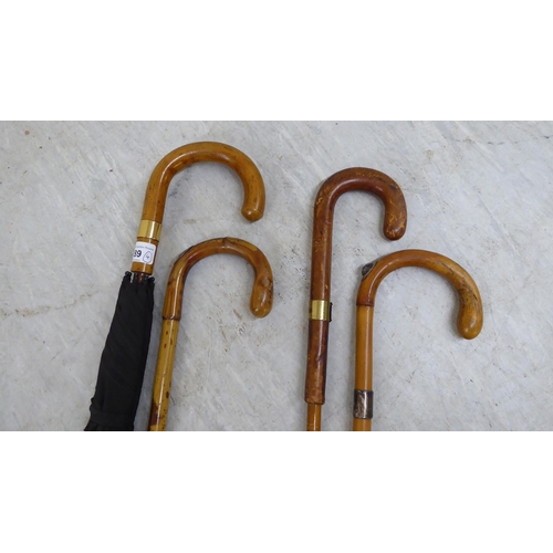 89 - Four wooden walking canes/umbrellas, one with a 9ct gold cap