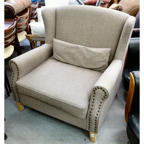 439 - A modern grey fabric upholstered oversize, wingback chair, raised on block feet