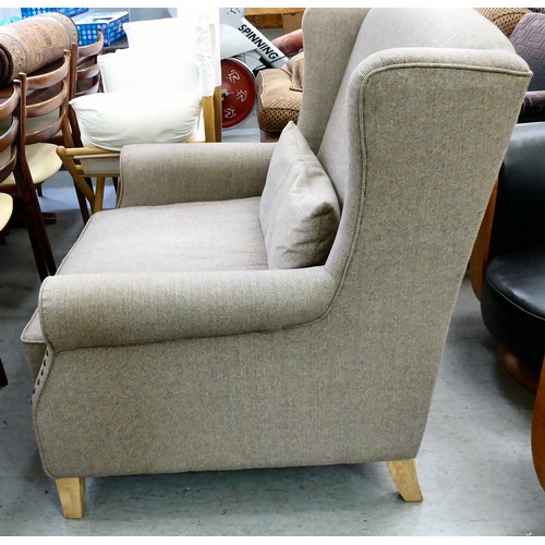 439 - A modern grey fabric upholstered oversize, wingback chair, raised on block feet