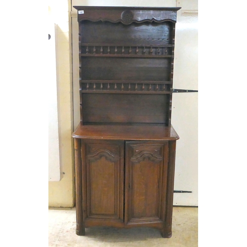 100 - An early 20thC oak two-part cottage dresser with two open shelves, over two panelled cupboard doors,... 