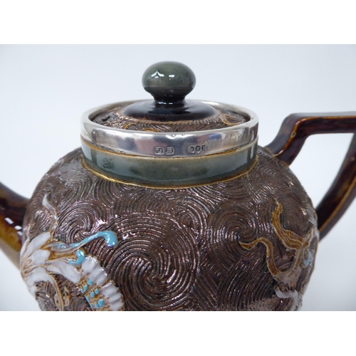 119 - A late Victorian Doulton Lambeth stoneware teapot of ovoid form with a silver collar and spout termi... 