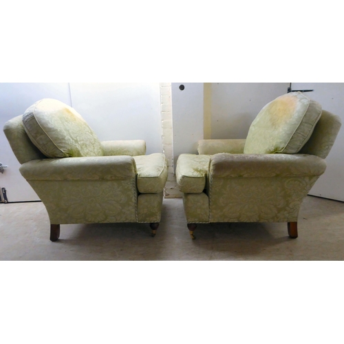 128 - A pair of modern floral patterned, old gold coloured fabric upholstered armchairs, raised on turned ... 