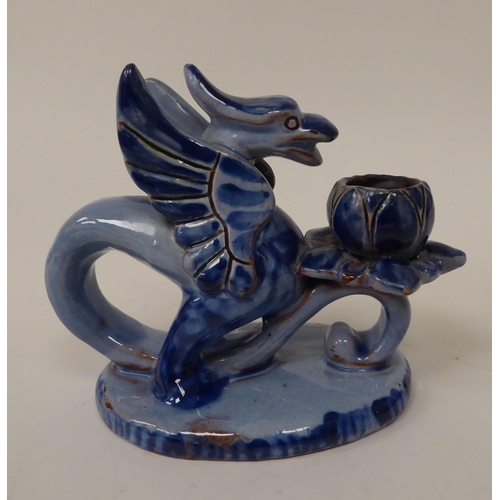 16 - An early 20thC Barum ware blue glazed pottery candle holder, fashioned as a griffin, on an oval base... 