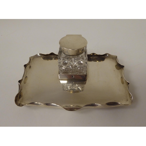 17 - A silver and cut glass inkwell with a hinged cap, on a crimped, rectangular tray  Hukin & H... 