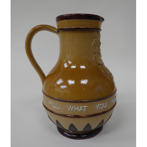 181 - A Doulton Lambeth stoneware water jug, the moulded maskhead figure above an inscription 'Fill What Y... 