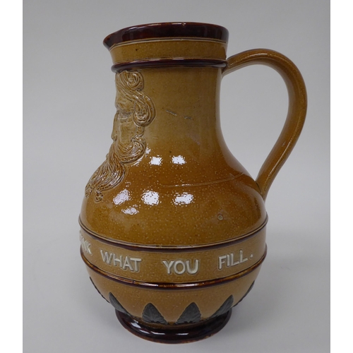 181 - A Doulton Lambeth stoneware water jug, the moulded maskhead figure above an inscription 'Fill What Y... 