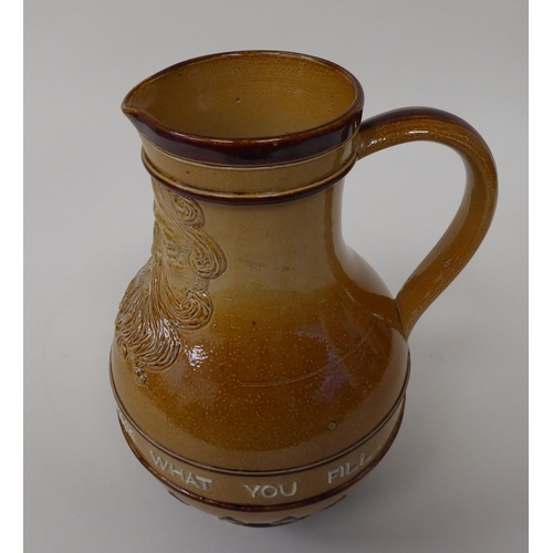 181 - A Doulton Lambeth stoneware water jug, the moulded maskhead figure above an inscription 'Fill What Y... 