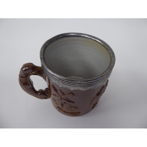 183 - A late 19thC brown stoneware mug with straight sides, a hunting dog handle, applied pewter rim and m... 