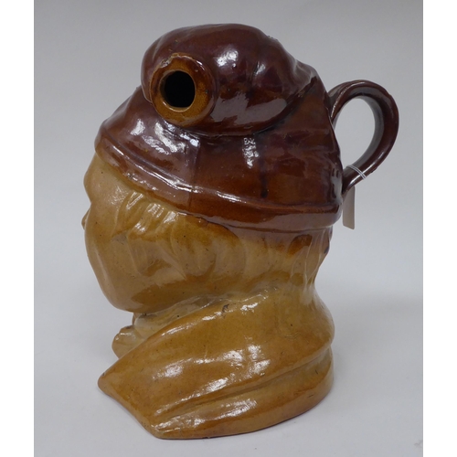 19 - A late 19thC two tone brown salt glazed earthenware novelty jug, fashioned as a smiling man, wearing... 