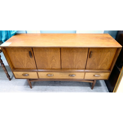 213 - A G-Plan teak sideboard with a pair of hinged doors, over three in-line drawers, raised on turned, t... 