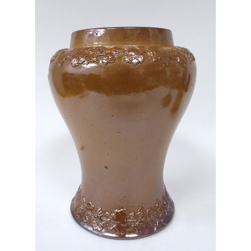 221 - A 20thC brown stoneware wine jar of waisted baluster form, decorated with trailing, fruiting vine or... 