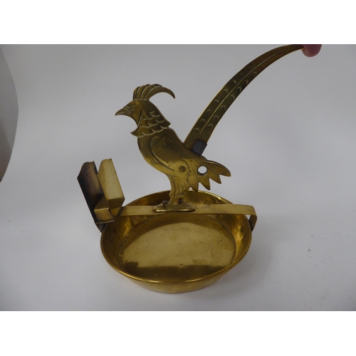 224 - A 20thC novelty brass combination cigar cutter and matchbox holder, fashioned as a bird on a saucer ... 