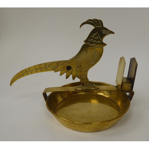 224 - A 20thC novelty brass combination cigar cutter and matchbox holder, fashioned as a bird on a saucer ... 