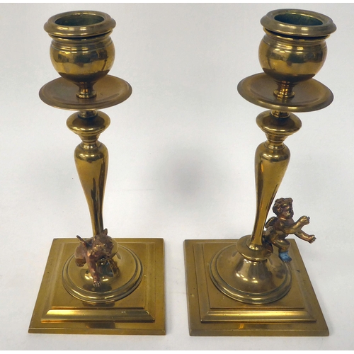 238 - A pair of late 19thC brass candlesticks with knopped, tapered stems, each surmounted by a cherubic f... 