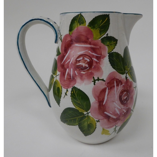 24 - A Wemyss Ware pottery jug of tapered, bulbous form, traditionally decorated in red roses and green l... 