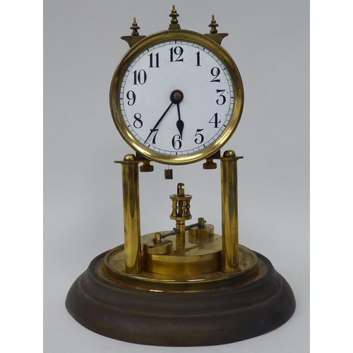 25 - An early 20thC lacquered brass cased torsion timepiece with an exposed mechanism, faced by a white e... 