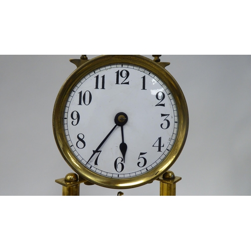 25 - An early 20thC lacquered brass cased torsion timepiece with an exposed mechanism, faced by a white e... 