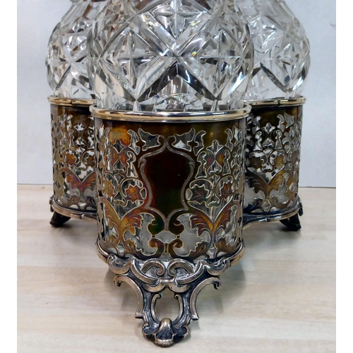 282 - An ornate cast silver plated cruet stand, hosting three glass decanters with stoppers