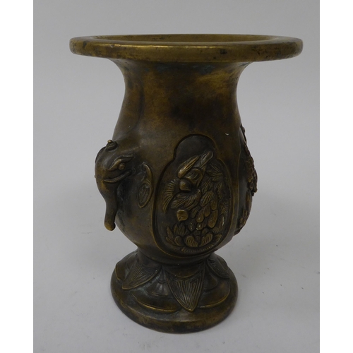 29 - An early 20thC cast bronze vase with opposing elephant head handles and oval vignettes, on a flared ... 