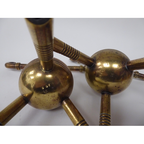 34 - A pair of late Victorian burnished brass hearth implement holders, on decoratively turned, tripod le... 