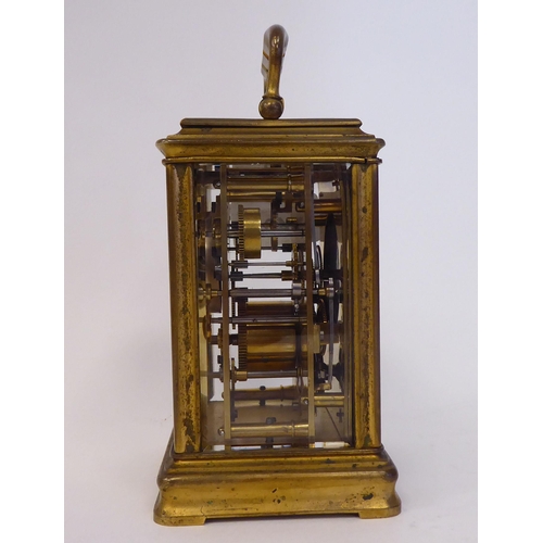 40 - A mid 20thC gilded brass cased carriage clock with bevelled glass panels and a folding top handle; t... 