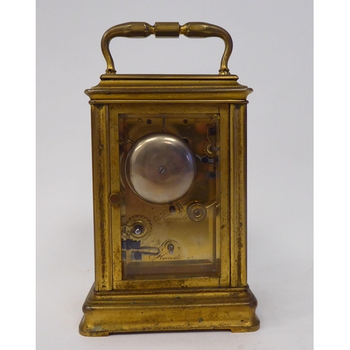 40 - A mid 20thC gilded brass cased carriage clock with bevelled glass panels and a folding top handle; t... 