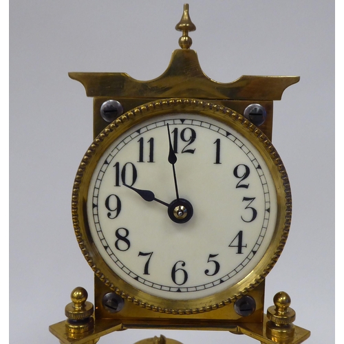 43 - An early 20thC lacquered brass cased torsion timepiece with an exposed mechanism, faced by a painted... 