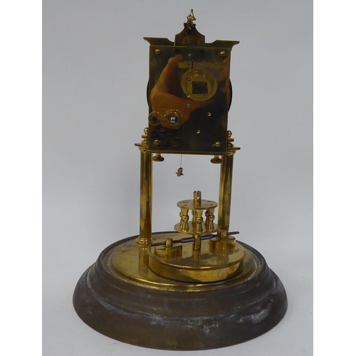 43 - An early 20thC lacquered brass cased torsion timepiece with an exposed mechanism, faced by a painted... 